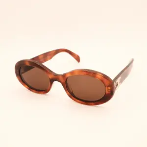 Vintage zonnebril met ovale bruine schildpad montuur en gouden detail op de poot